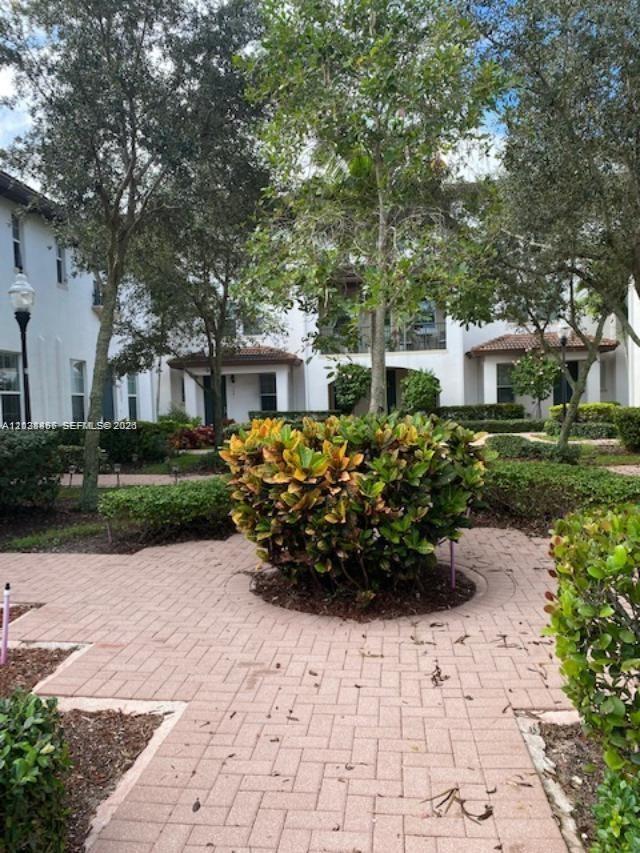 A paved walkway leads toward a multi-story residential building surrounded by trees and landscaping — 11835 SW 27th St # 801, Miramar FL 33025, MIRAMAR, FL