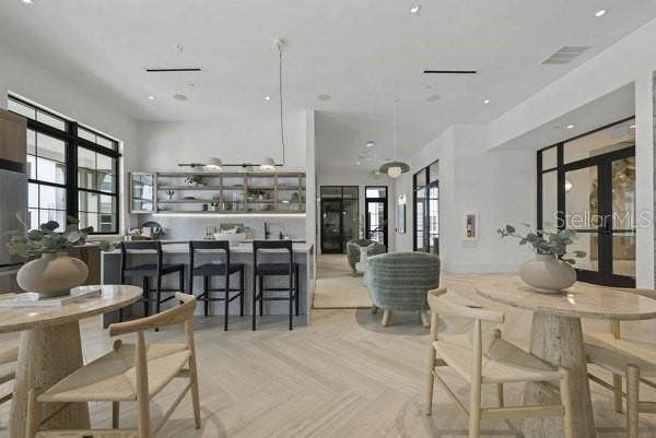 A bright, open-concept kitchen and dining area featuring light wood floors and modern furniture — 2790 GRAND AVE STREET UNIT A2, ST PETERSBURG, FL