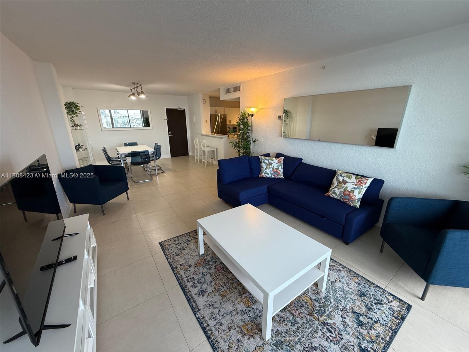 A living room features a blue sectional sofa, a white coffee table, and tile flooring — 1500 Bay Rd # 1534S, Miami Beach FL 33139, MIAMI BEACH, FL