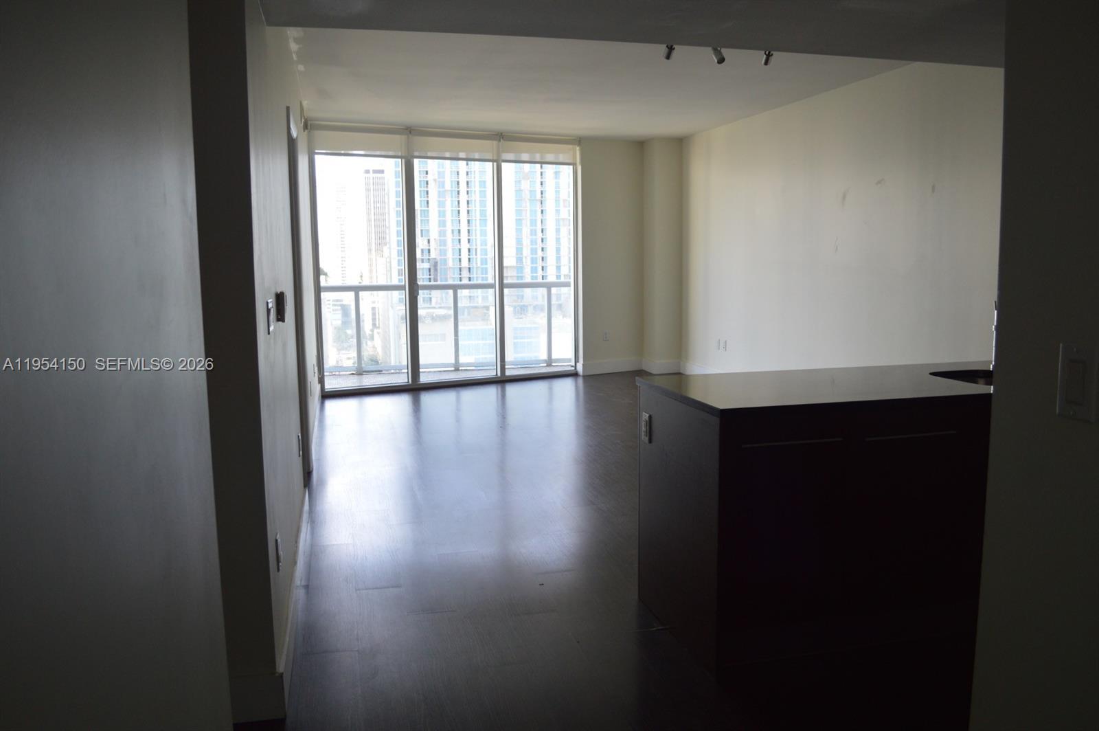 An empty room with dark wood flooring, a kitchen island, and floor-to-ceiling windows — 475 Brickell Ave # 1814, Miami FL 33131, MIAMI, FL