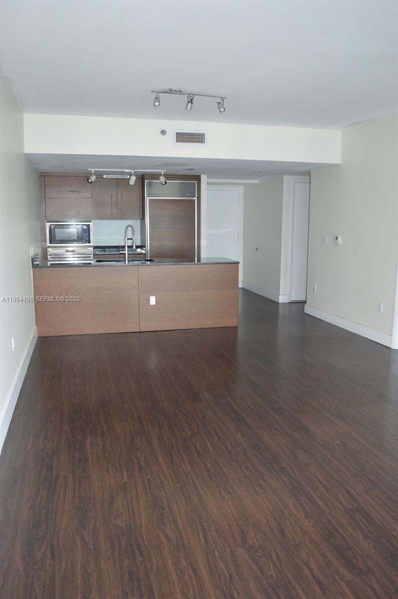 An open-concept kitchen with wood cabinets and a breakfast bar overlooks a living area — 475 Brickell Ave # 1814, Miami FL 33131, MIAMI, FL
