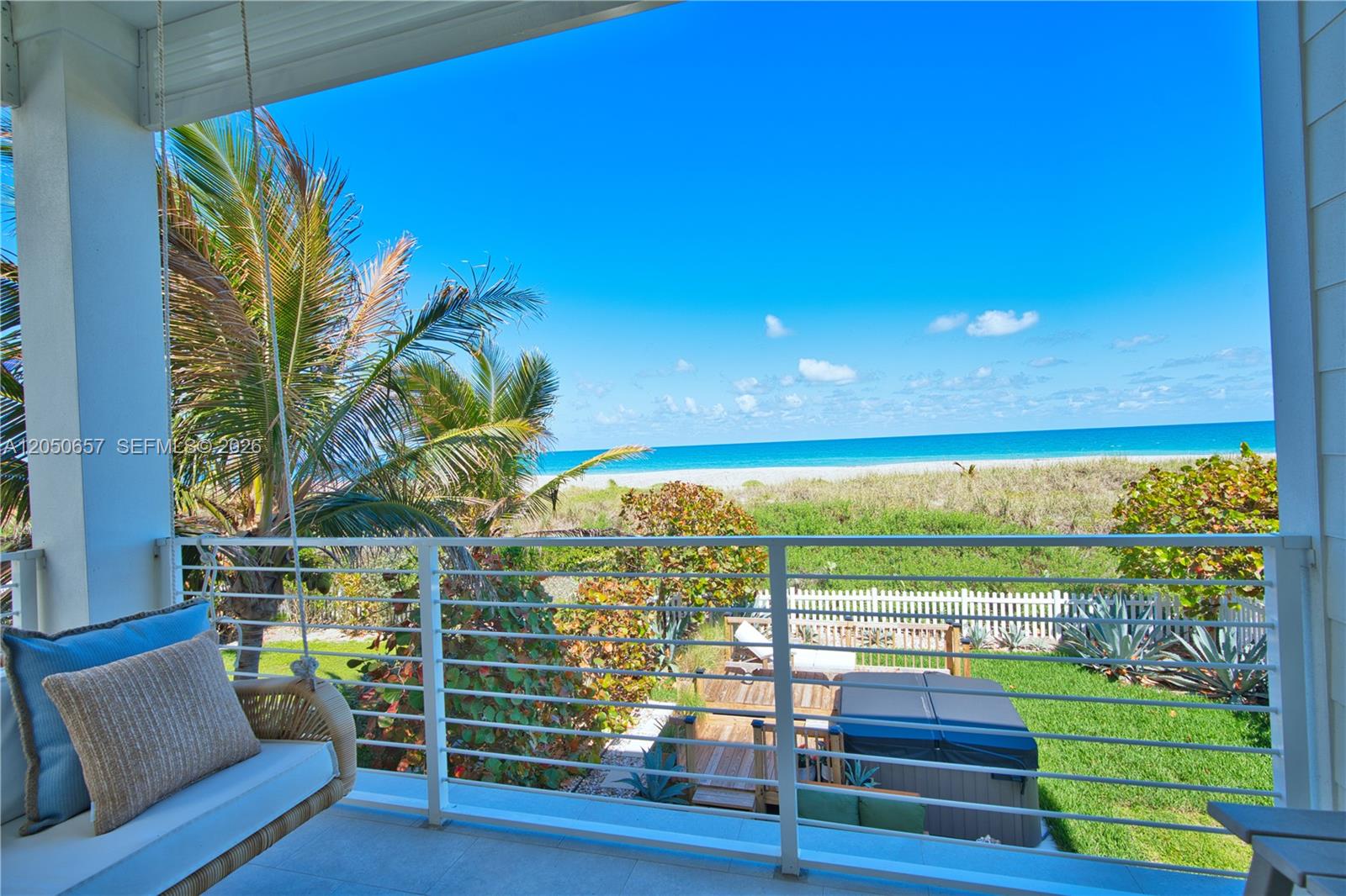 A balcony with a hanging chair overlooks a backyard, a hot tub, and the ocean — 5120 Watersong Way, Fort Pierce FL 34949, FORT PIERCE, FL