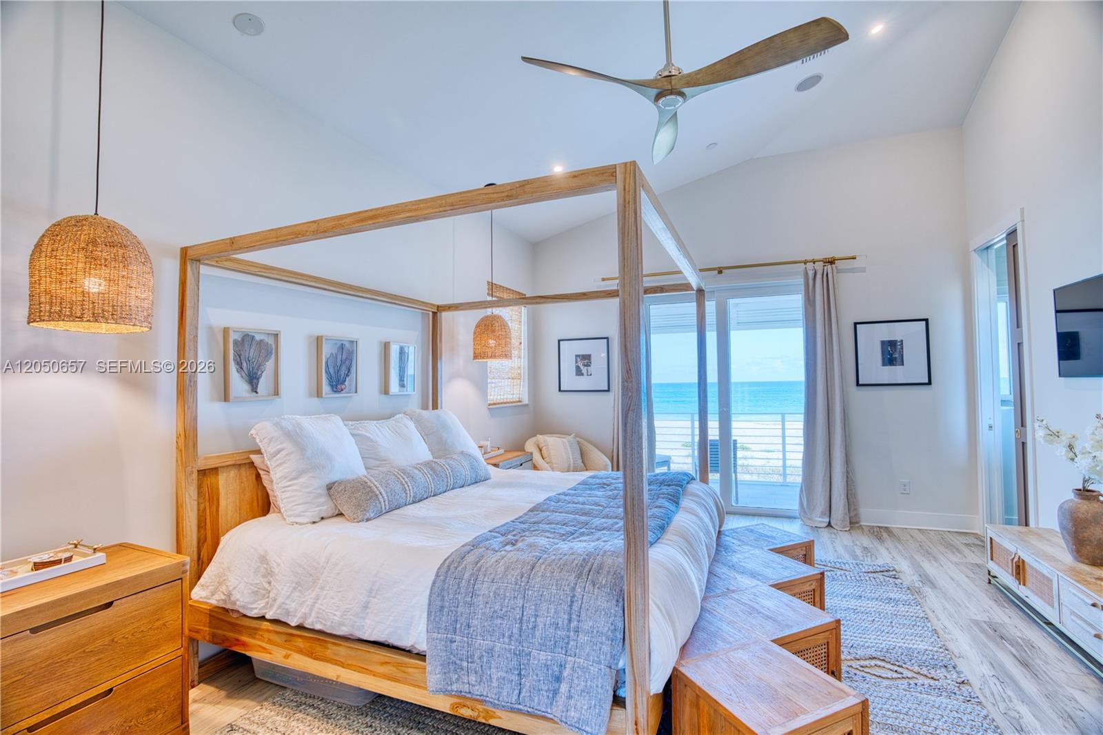 A bedroom features a wooden canopy bed, a blue quilt, and a view of the ocean — 5120 Watersong Way, Fort Pierce FL 34949, FORT PIERCE, FL