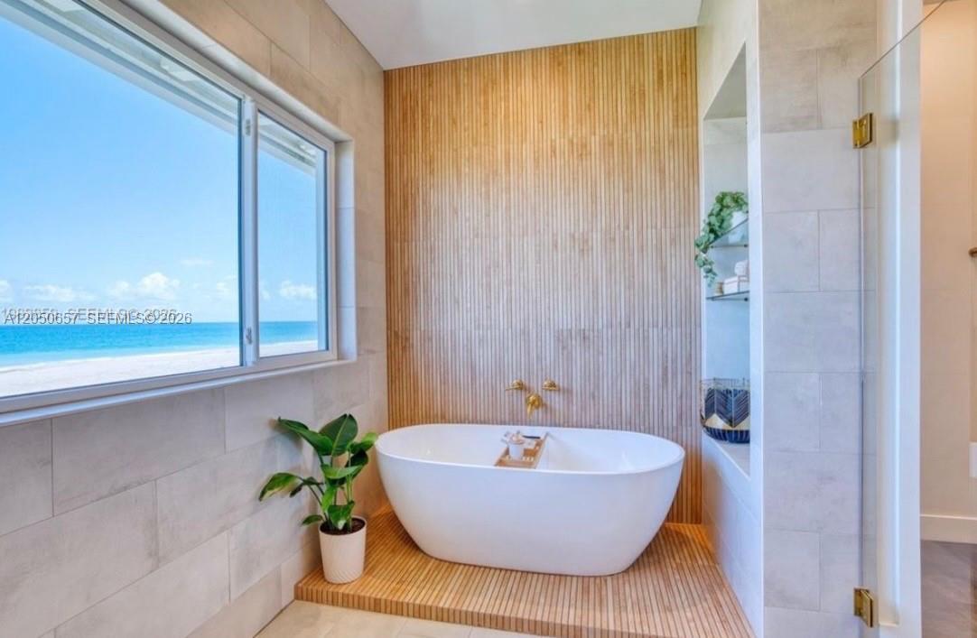 A modern bathroom features a freestanding white tub against a vertical wood-slat accent wall — 5120 Watersong Way, Fort Pierce FL 34949, FORT PIERCE, FL