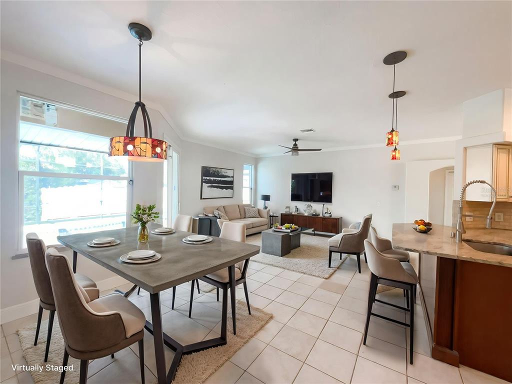 An open-concept living and dining area features tile flooring, a modern kitchen island, and pendant lighting — 4241 SETTLERS COURT, ST CLOUD, FL