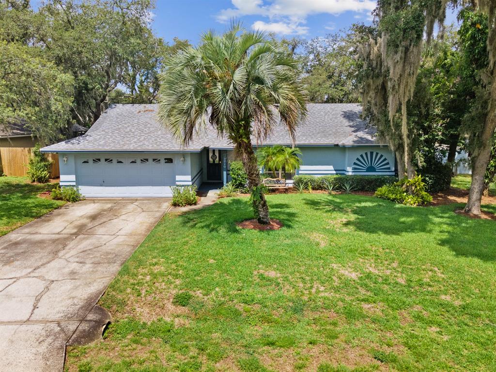 A single-story house with a light blue exterior, a two-car garage, and a large palm tree — 7710 NATURE TRAIL, LAKELAND, FL