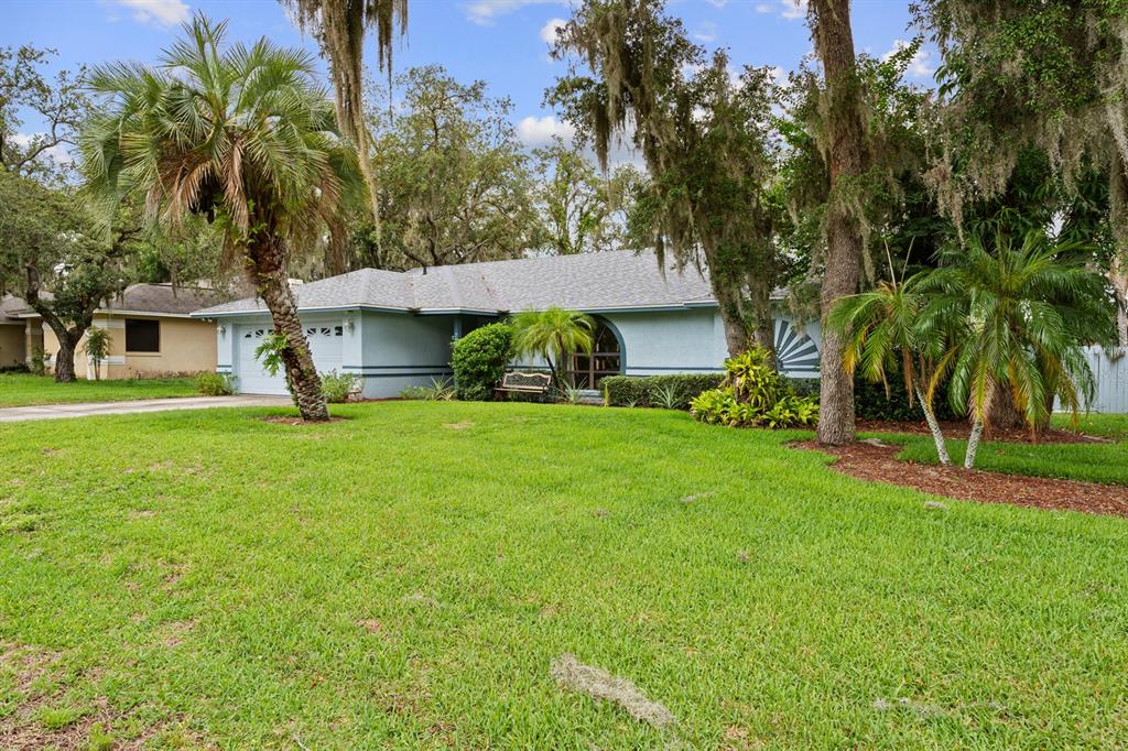 A light blue single-story house with a palm tree in the front yard — 7710 NATURE TRAIL, LAKELAND, FL