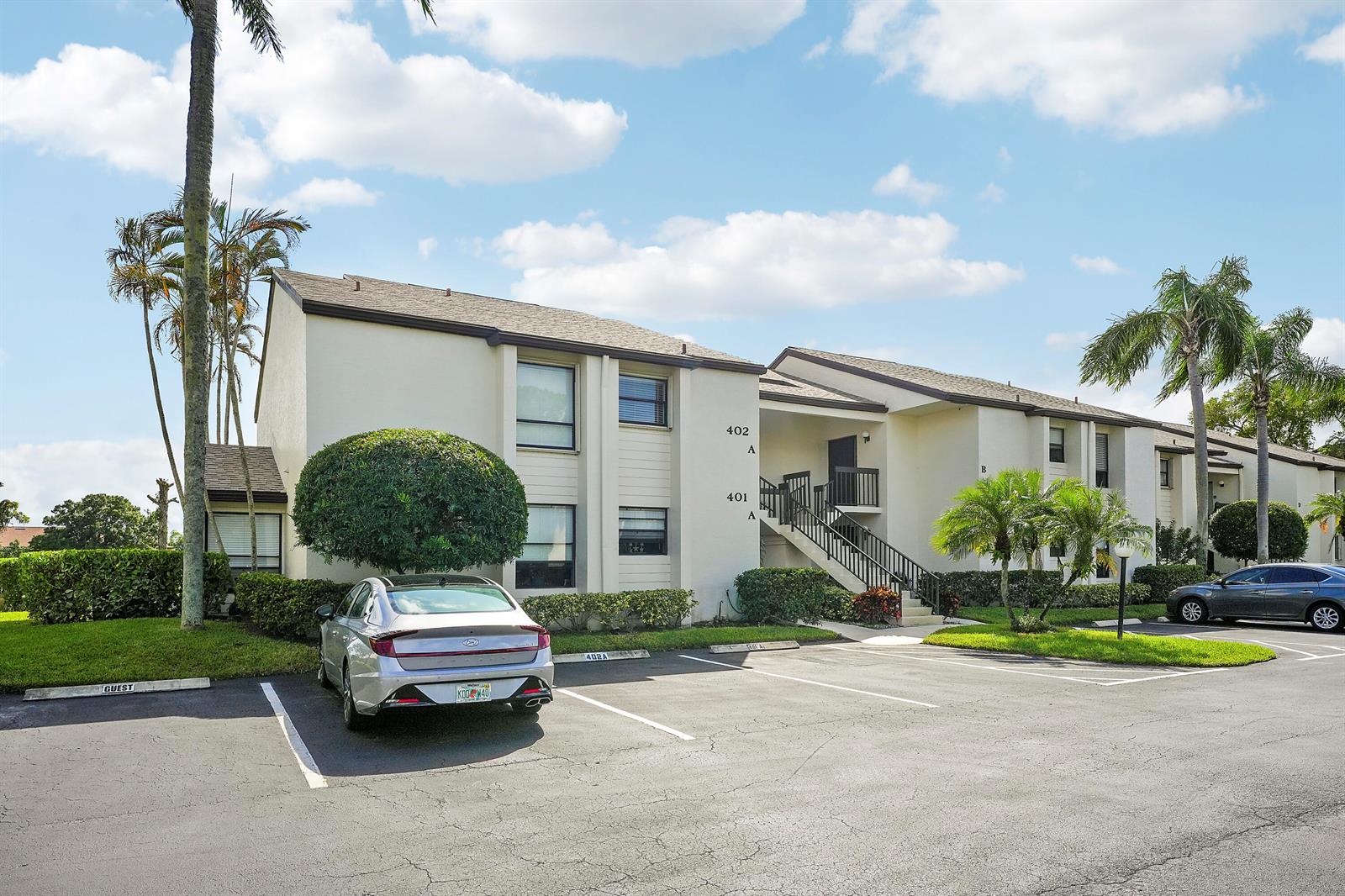 A two-story apartment building with a parking lot and palm trees under a blue sky — 402 Wingfoot Drive # B, Jupiter FL 33458, JUPITER, FL