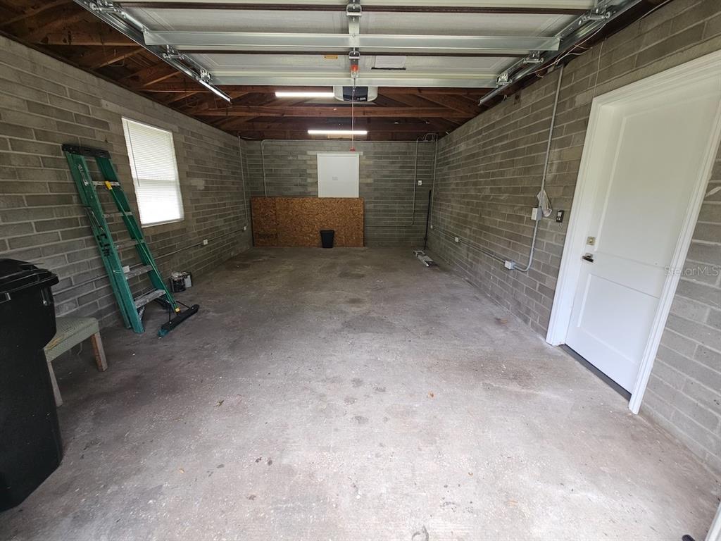 An empty garage features concrete block walls, a concrete floor, and an exposed wood ceiling — 903 NW 33RD AVENUE, GAINESVILLE, FL