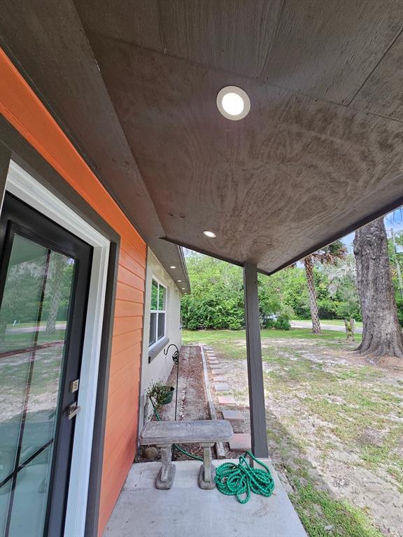 A covered porch with recessed lighting, a concrete floor, and an orange-sided exterior wall — 903 NW 33RD AVENUE, GAINESVILLE, FL