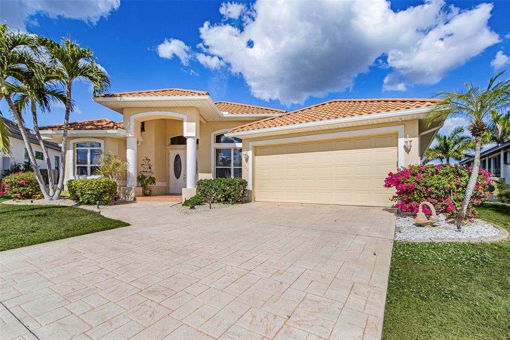A single-story house with a beige stucco exterior, a tiled roof, and a paved driveway — 400 GUN CAY LANE, PUNTA GORDA, FL