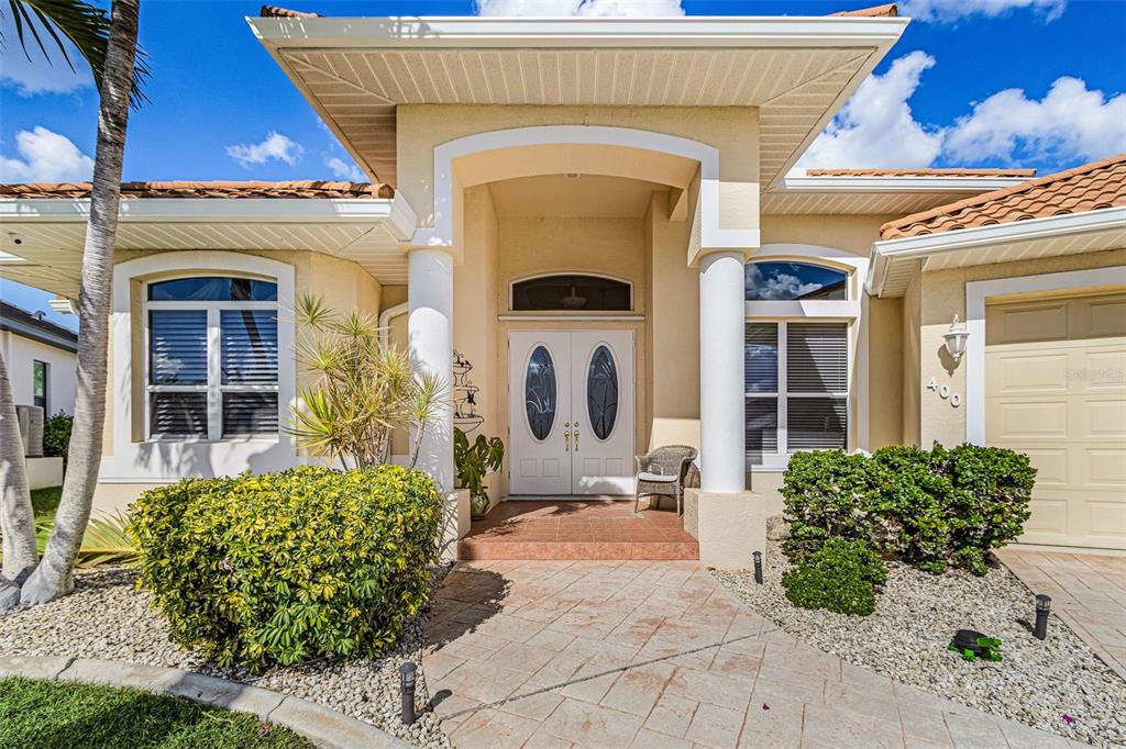The exterior of a single-story house features a covered entryway with white columns and double doors — 400 GUN CAY LANE, PUNTA GORDA, FL