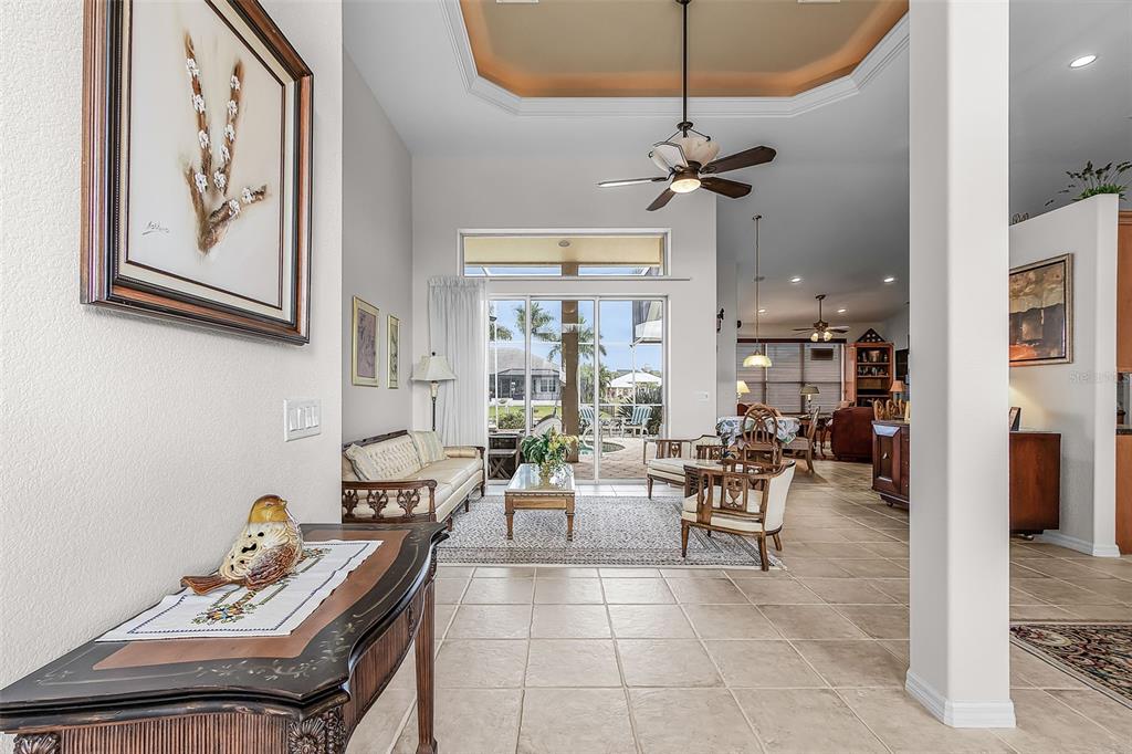 A bright living room features tile floors, a tray ceiling, and sliding doors to a pool — 400 GUN CAY LANE, PUNTA GORDA, FL