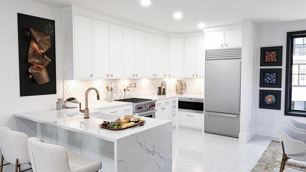 A modern kitchen features white cabinetry, marble countertops, a stainless steel refrigerator, and gold fixtures — 2360 OCEAN SHORE BOULEVARD UNIT 4, ORMOND BEACH, FL