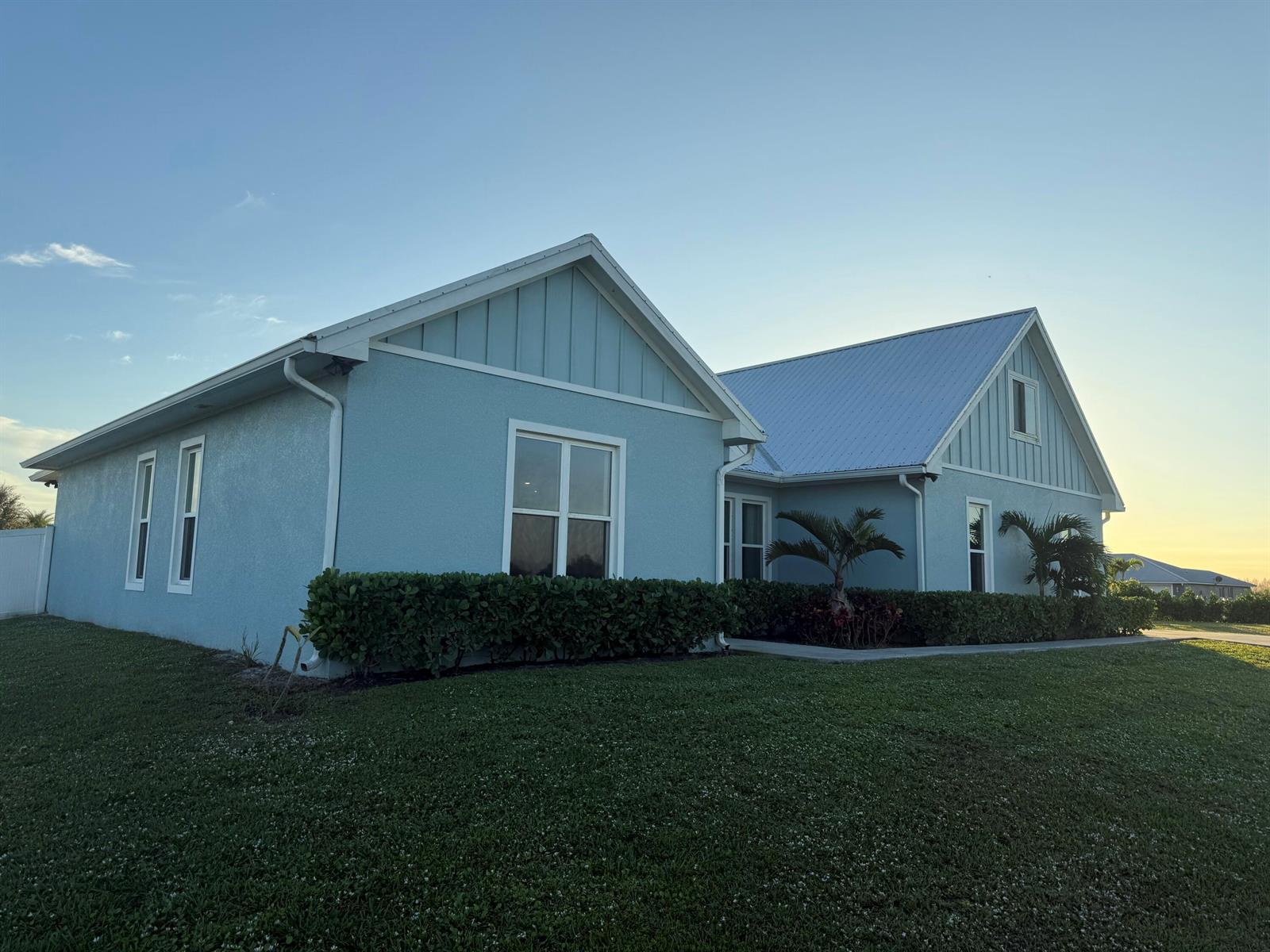 A light blue house with a metal roof and a manicured hedge in the front yard — 3533 Sky Valley Lane, Clewiston FL 33440, CLEWISTON, FL