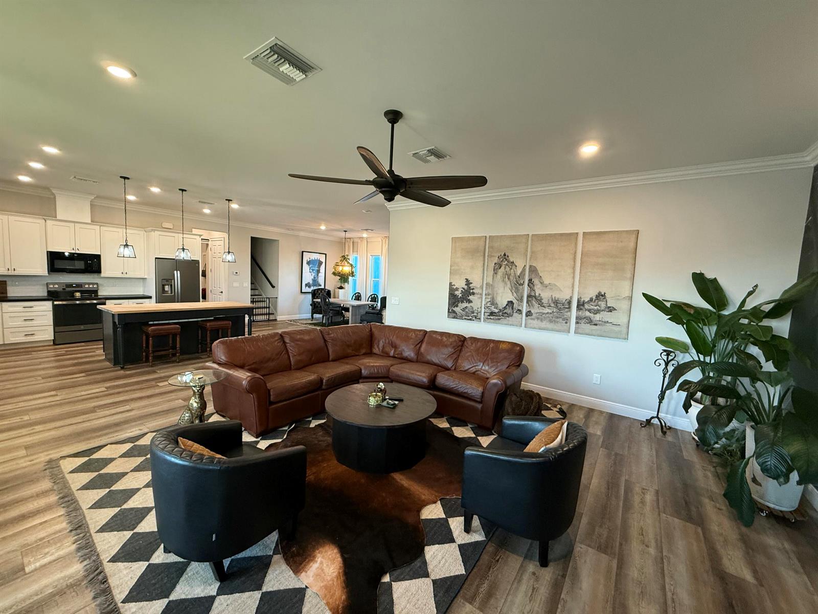 An open-concept living room with a brown leather sectional, black chairs, and a kitchen island — 3533 Sky Valley Lane, Clewiston FL 33440, CLEWISTON, FL