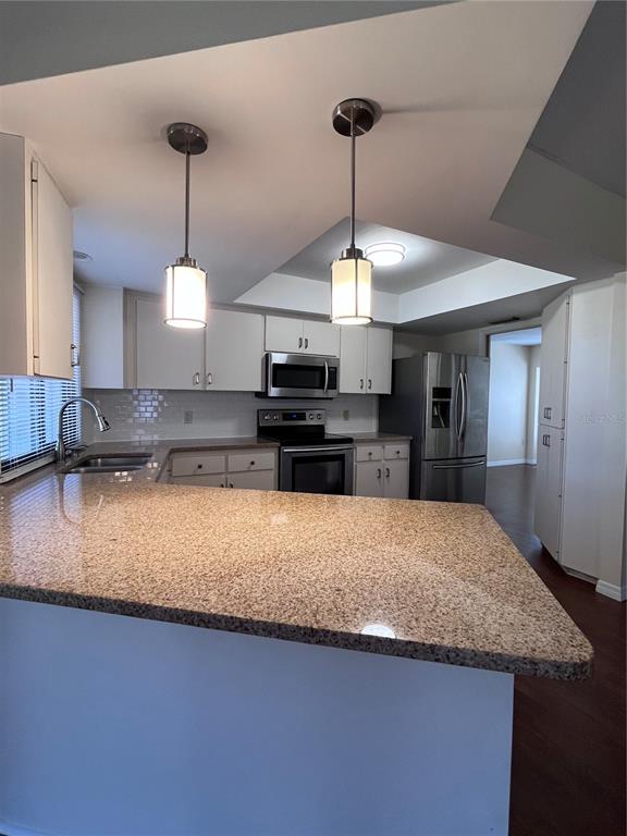 A kitchen features white cabinets, granite countertops, stainless steel appliances, and two pendant lights — 5816 MONROE ROAD, VENICE, FL