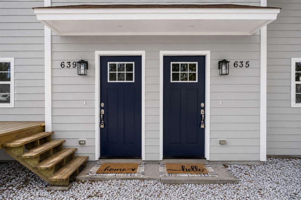 Two dark blue front doors with windows and house numbers sit side-by-side on a gray exterior — 635 6TH AVENUE S, JACKSONVILLE BEACH, FL
