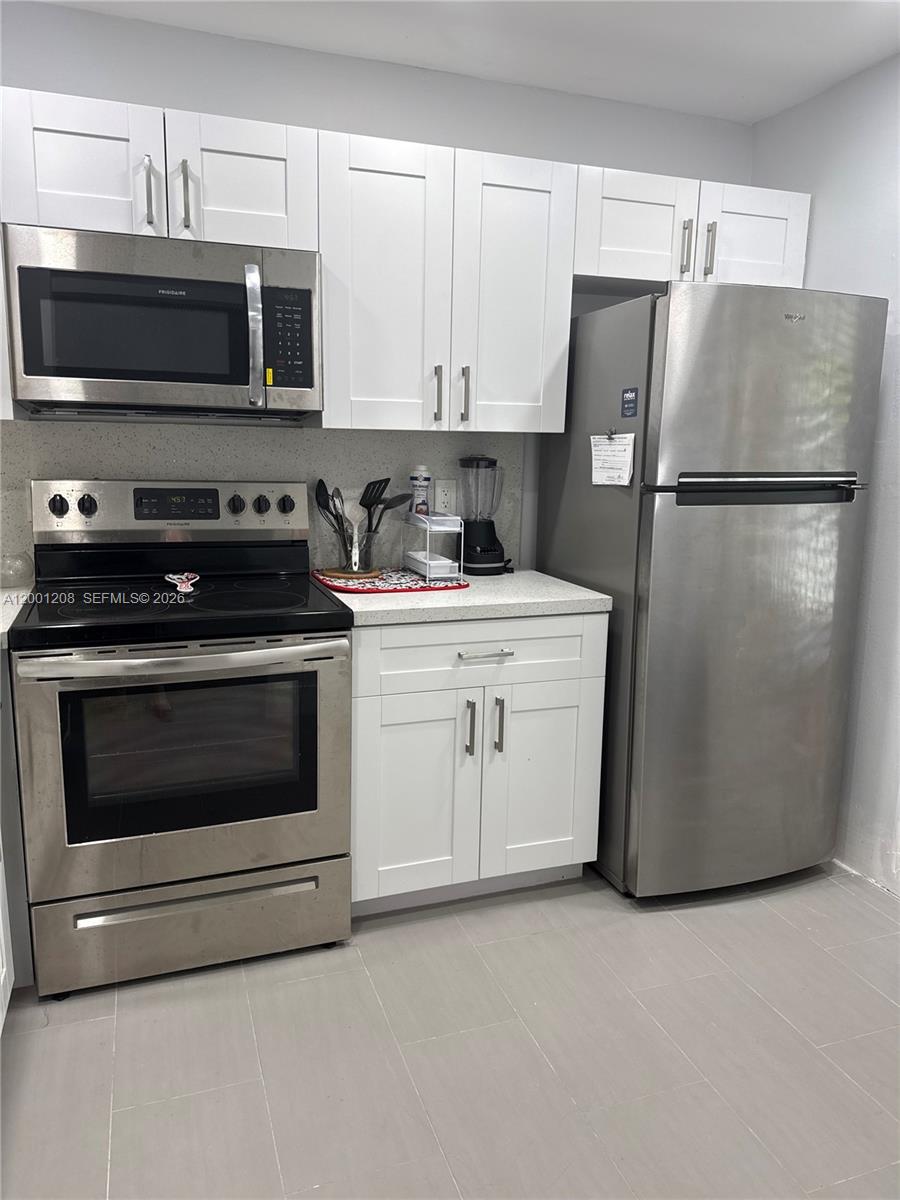 A kitchen features white shaker cabinets, stainless steel appliances, and light-colored countertops — 1102 Bahama Bnd # D2, Coconut Creek FL 33066, COCONUT CREEK, FL