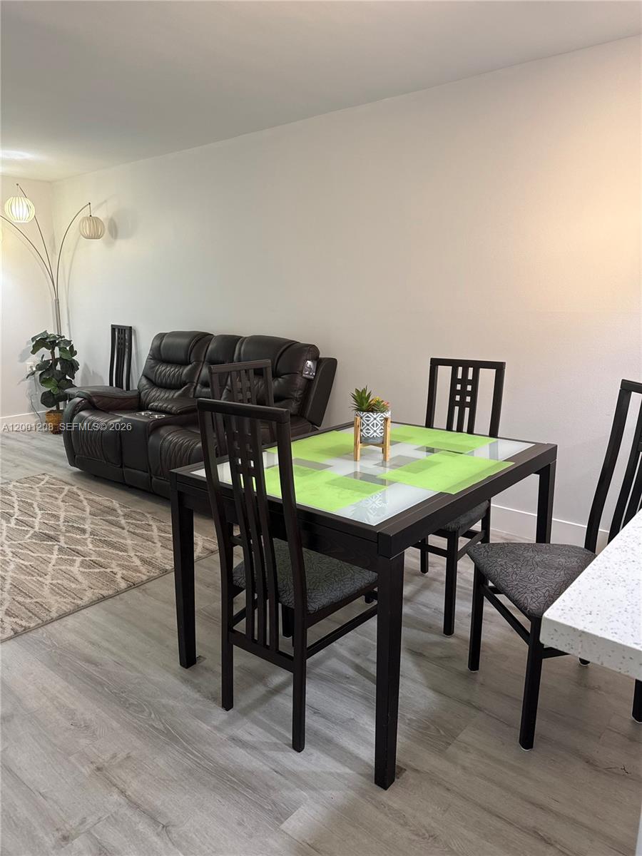 A dining area with a glass-top table sits next to a dark leather sofa — 1102 Bahama Bnd # D2, Coconut Creek FL 33066, COCONUT CREEK, FL