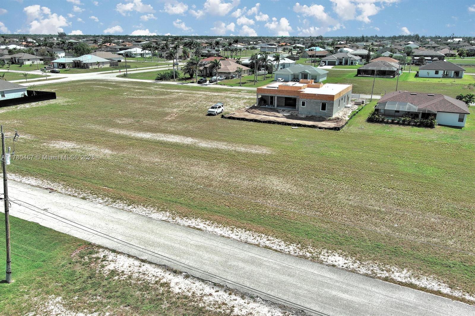 An aerial view shows a large vacant lot with a house under construction — 1037 NW 37TH PL, Cape Coral FL 33993, CAPE CORAL, FL