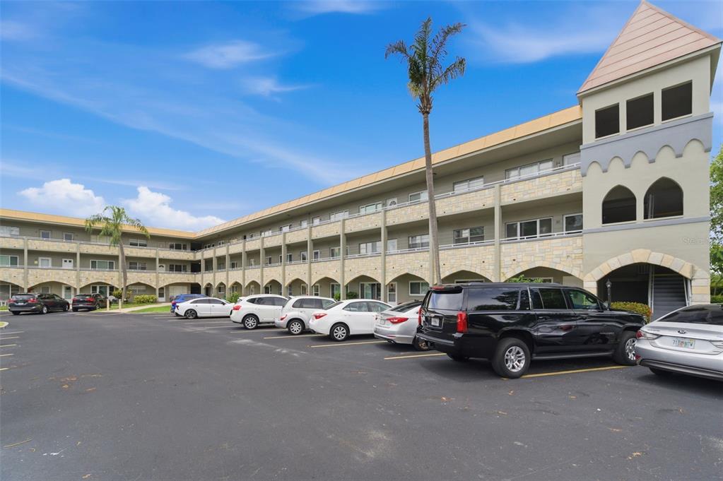 A three-story apartment building with a parking lot and several parked cars in front — 2462 BRAZILIA DRIVE UNIT 70, CLEARWATER, FL