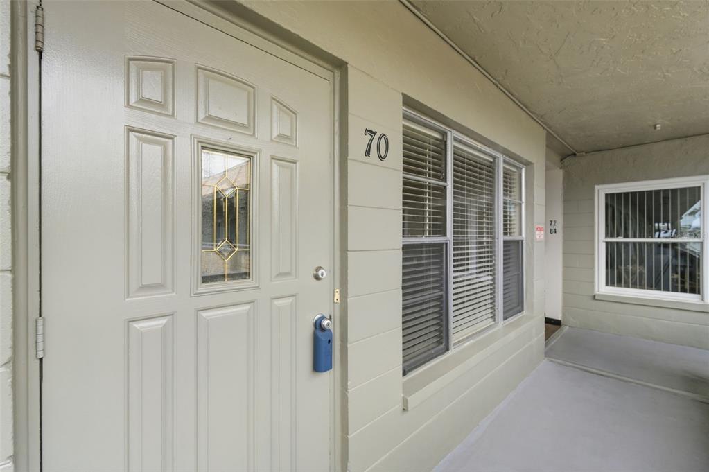 A light-colored exterior door with a window and the number 70 sits beside windows — 2462 BRAZILIA DRIVE UNIT 70, CLEARWATER, FL