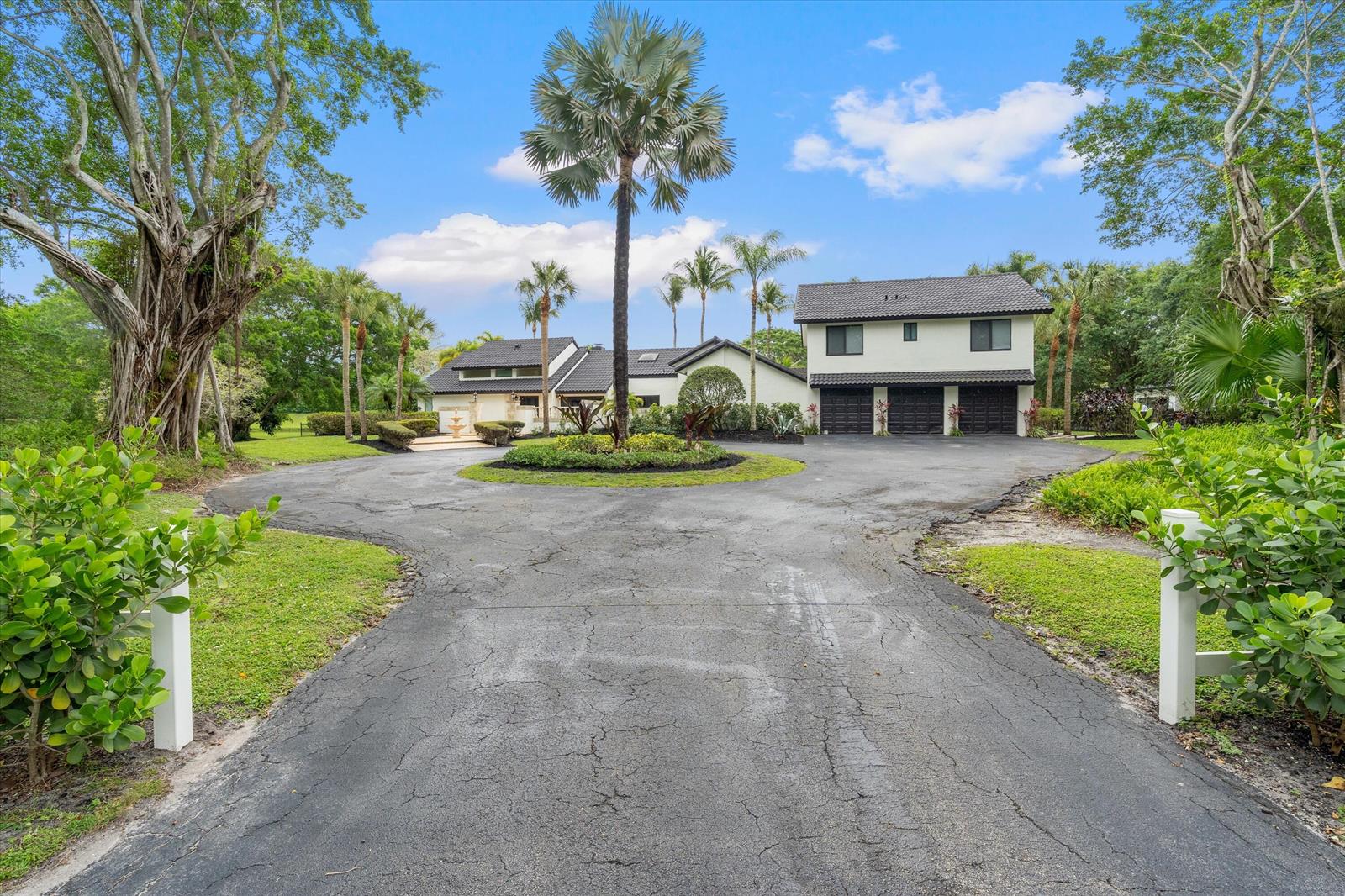A large house with a circular driveway, palm trees, and a three-car garage — 10076 El Caballo Court, Delray Beach FL 33446, DELRAY BEACH, FL