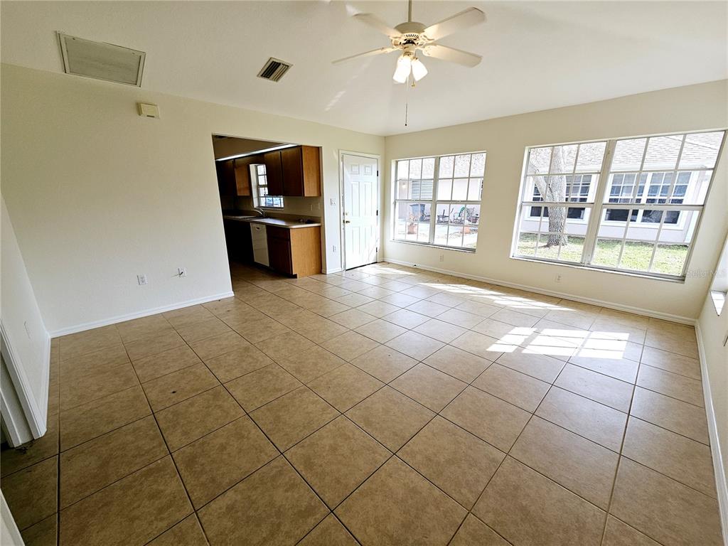 An open-concept living area features tan tile flooring, a ceiling fan, and large windows — 66 N MCCALL, ENGLEWOOD, FL