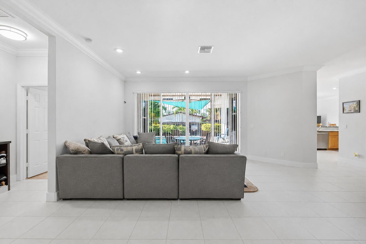 A gray sectional sofa sits in a bright living room with white tile flooring — 517 SE 7TH Avenue, Deerfield Beach FL 33441, DEERFIELD BEACH, FL