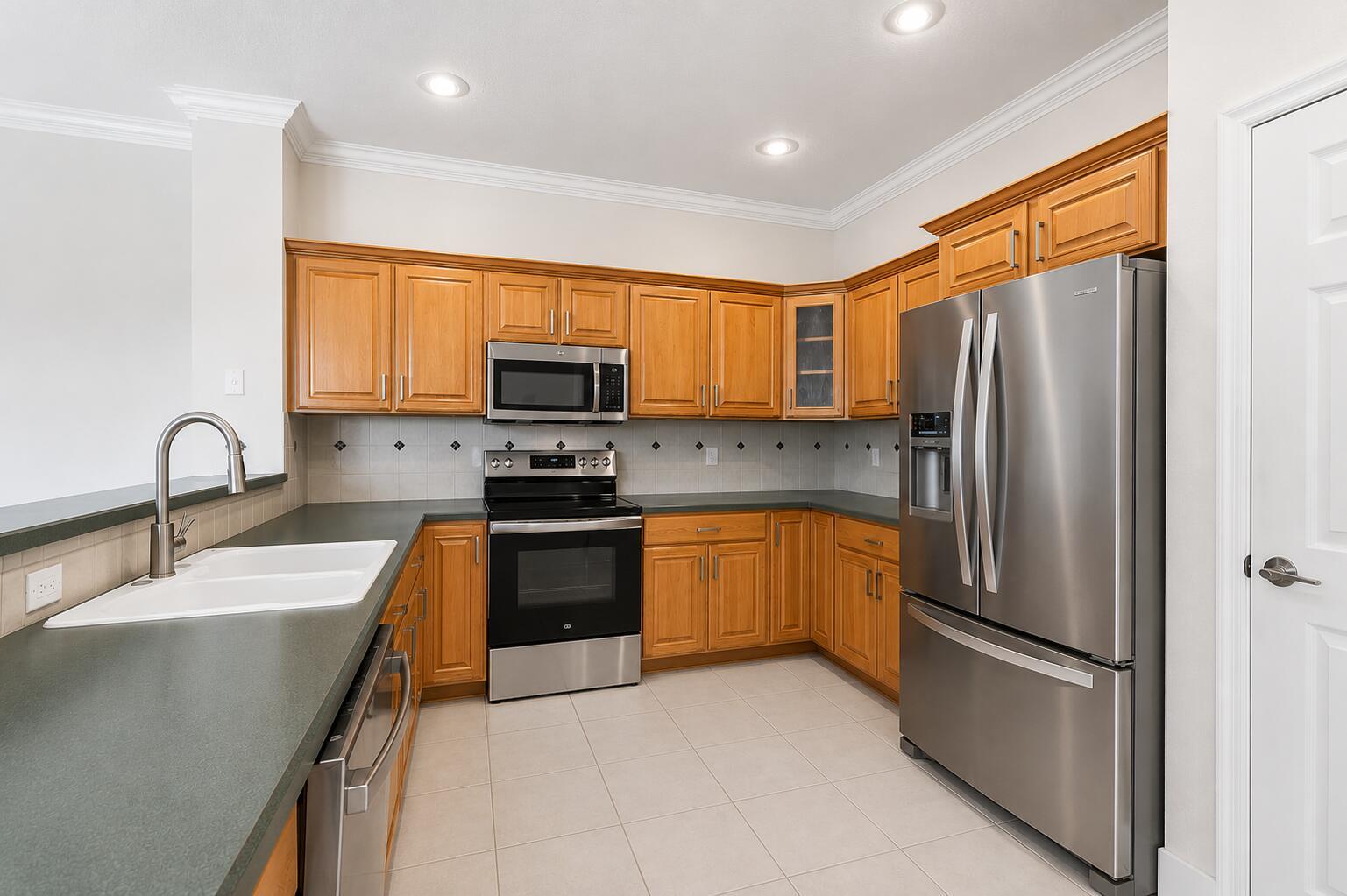A kitchen with wood cabinets, stainless steel appliances, and dark countertops on a tile floor — 517 SE 7TH Avenue, Deerfield Beach FL 33441, DEERFIELD BEACH, FL