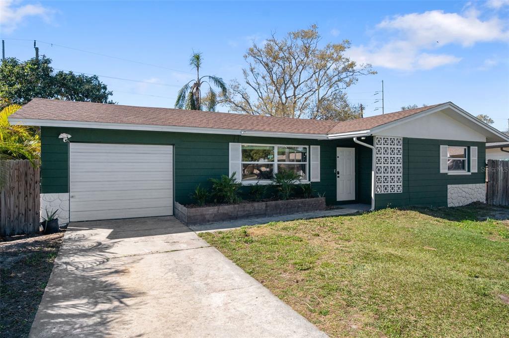 A single-story house with green siding, a white garage door, and a concrete driveway — 6522 112TH STREET, SEMINOLE, FL