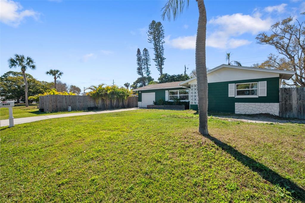 A single-story house with green siding and a white stone base sits on a lawn — 6522 112TH STREET, SEMINOLE, FL