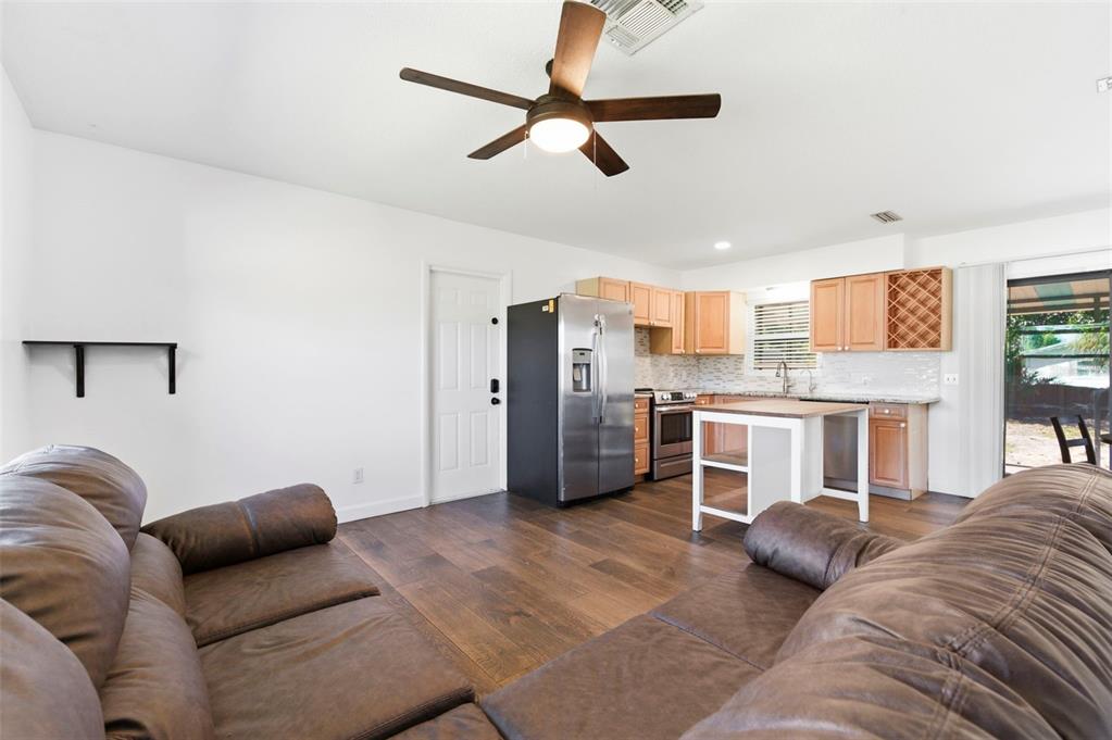 A living room with brown leather sofas opens into a kitchen with wood cabinets — 6522 112TH STREET, SEMINOLE, FL