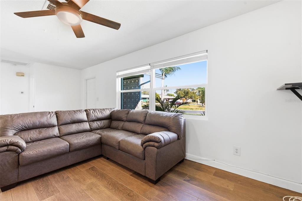 A living room features a large brown sectional sofa, wood-look flooring, and a ceiling fan — 6522 112TH STREET, SEMINOLE, FL