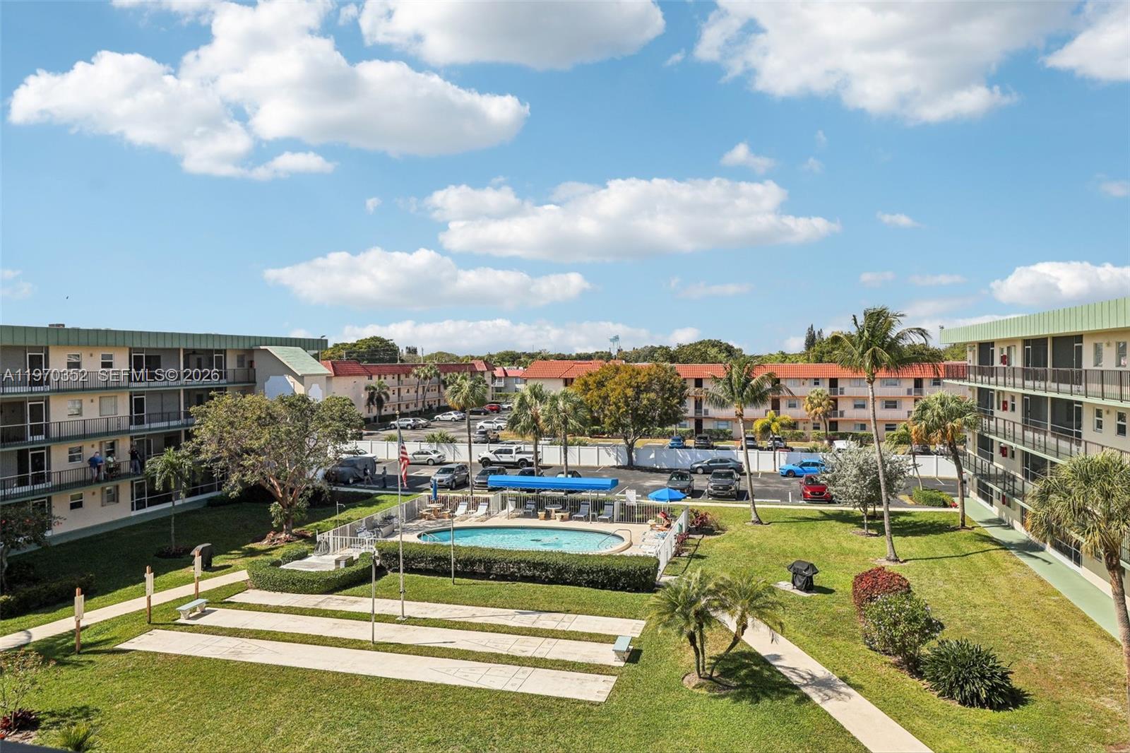 An aerial view shows a swimming pool, shuffleboard courts, and parking between two apartment buildings — 804 SE 7th St # 402, Deerfield Beach FL 33441, DEERFIELD BEACH, FL