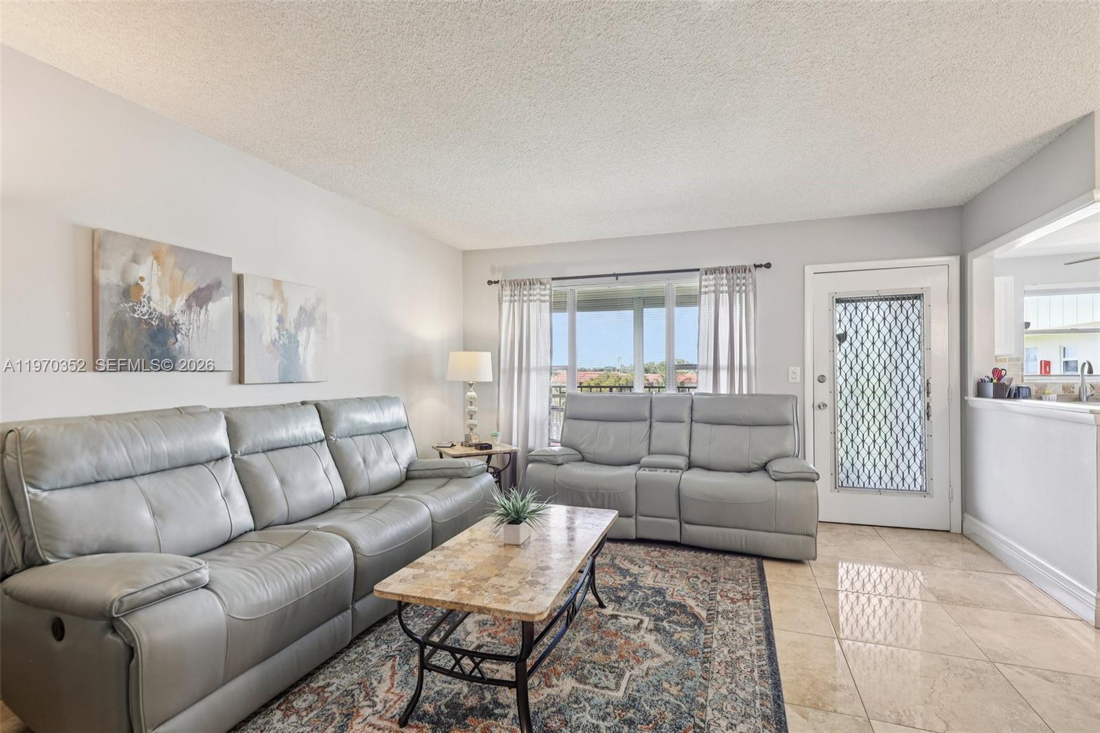 A living room features light gray leather sofas, a stone coffee table, and tile flooring — 804 SE 7th St # 402, Deerfield Beach FL 33441, DEERFIELD BEACH, FL