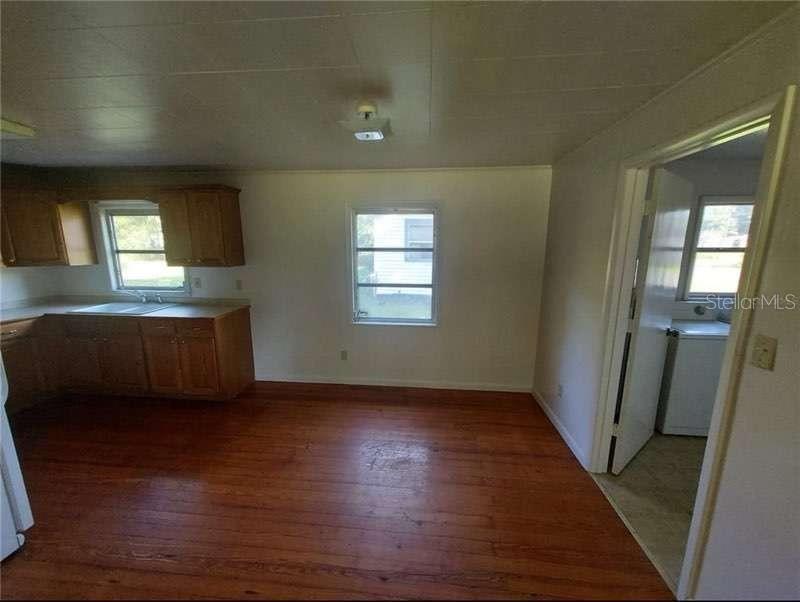 A kitchen with wood cabinets, hardwood floors, and a doorway leading to a laundry area — 1551 NE 29TH STREET, OCALA, FL