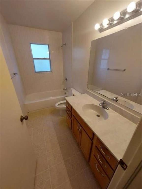 A bathroom features a wooden vanity with a white countertop, a mirror, and a tub-shower — 1551 NE 29TH STREET, OCALA, FL