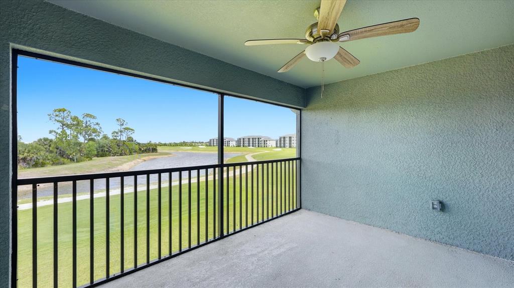 A covered balcony with a ceiling fan, black metal railing, and a view of a pond — 17475 OPAL SAND DRIVE UNIT 208, VENICE, FL