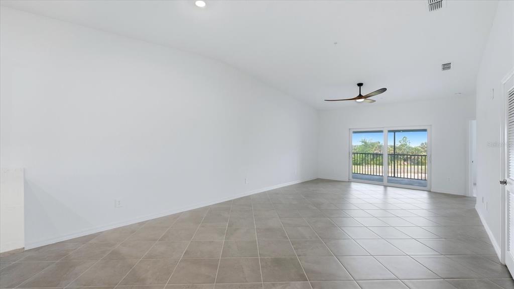 An empty room with white walls, tile flooring, a ceiling fan, and a sliding glass door — 17475 OPAL SAND DRIVE UNIT 208, VENICE, FL