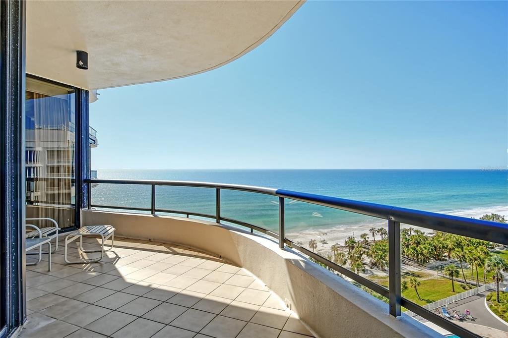 A curved balcony with tile flooring overlooks the ocean and a sandy beach below — 435 L AMBIANCE DRIVE UNIT L807, LONGBOAT KEY, FL