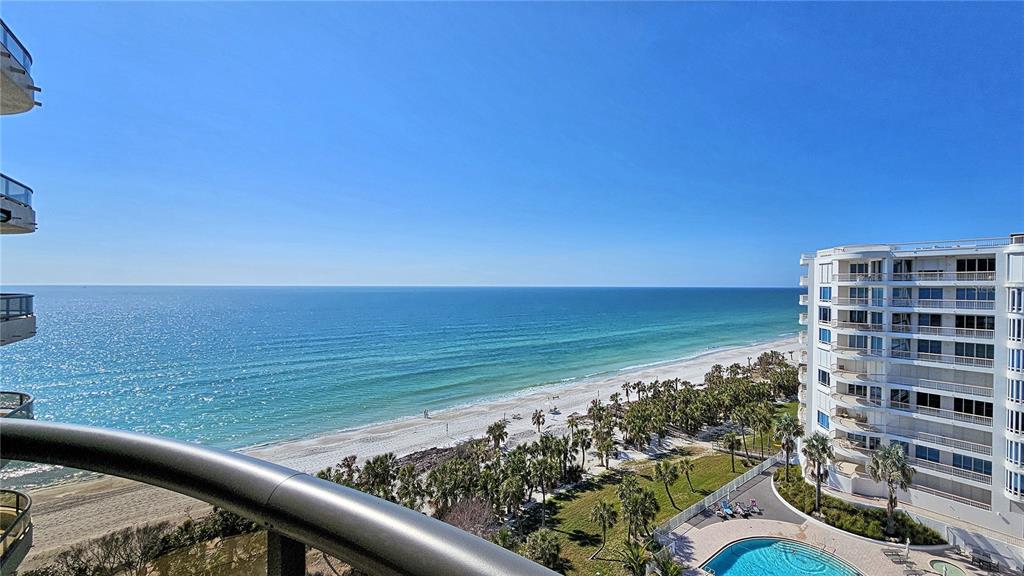 A high-angle view from a balcony overlooking a beach, ocean, and a neighboring resort building — 435 L AMBIANCE DRIVE UNIT L807, LONGBOAT KEY, FL