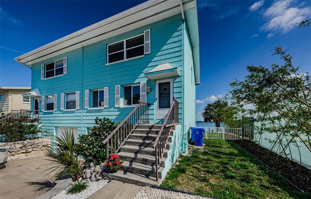 A two-story, light blue house with a staircase leading to the front entrance — 2672 ST JOSEPHS DRIVE, DUNEDIN, FL