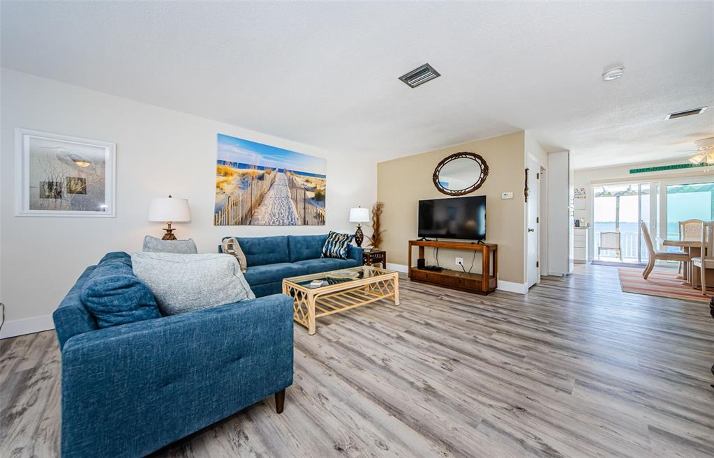 A living room features blue sofas, a wooden coffee table, and light wood-look flooring — 2672 ST JOSEPHS DRIVE, DUNEDIN, FL