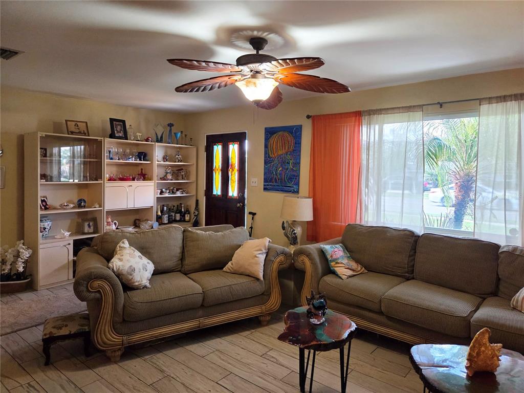 A living room features two sofas, a palm-leaf ceiling fan, and a built-in display shelf — 11066 102ND AVENUE N, SEMINOLE, FL