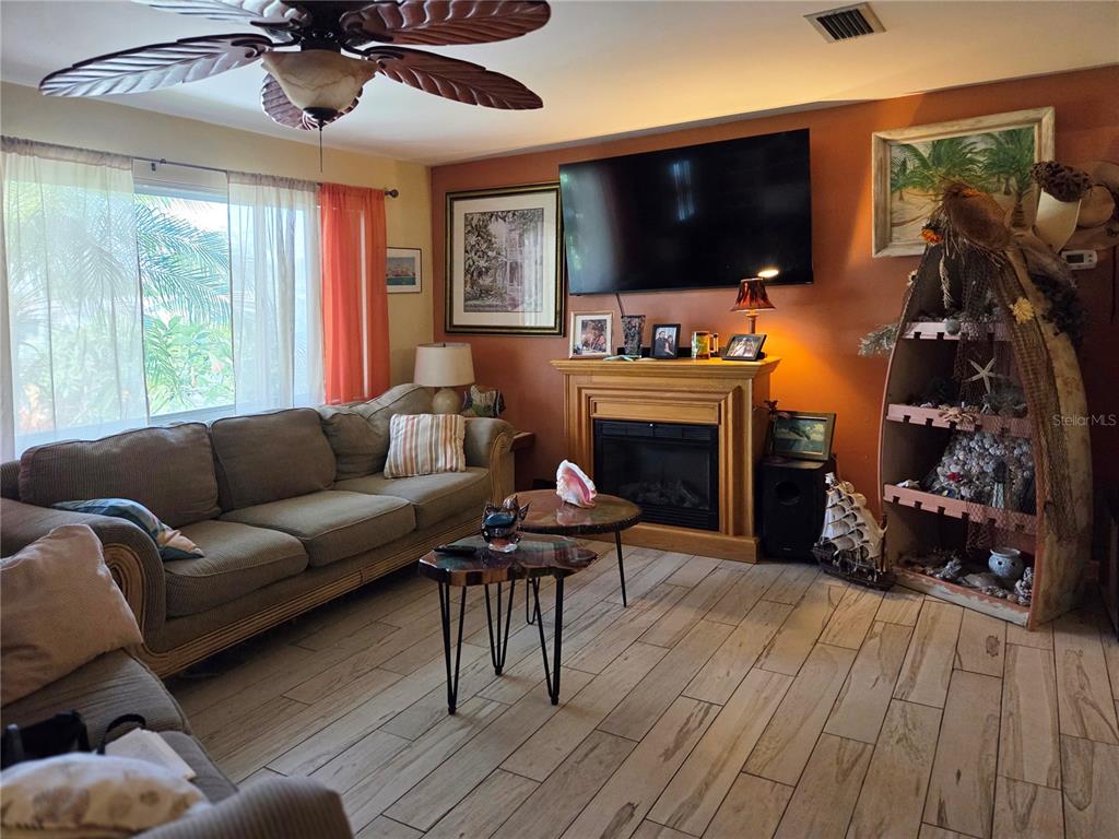 A living room features a fireplace, a television, a sofa, and a boat-shaped display shelf — 11066 102ND AVENUE N, SEMINOLE, FL