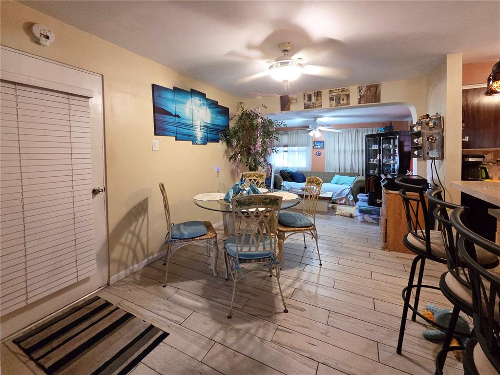 A dining area with a glass table, four chairs, and tile flooring leads into a living room — 11066 102ND AVENUE N, SEMINOLE, FL
