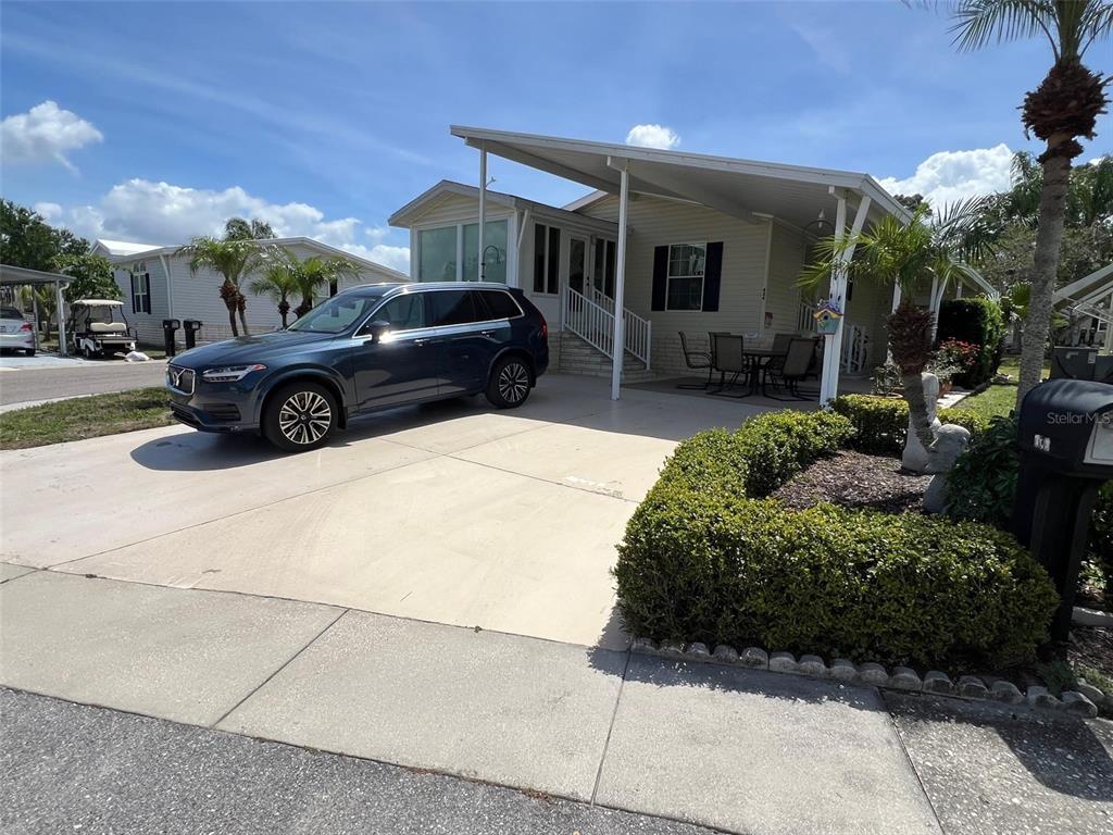 A dark blue SUV is parked on a concrete driveway in front of a manufactured home — 29250 US HIGHWAY 19 N UNIT 434, CLEARWATER, FL