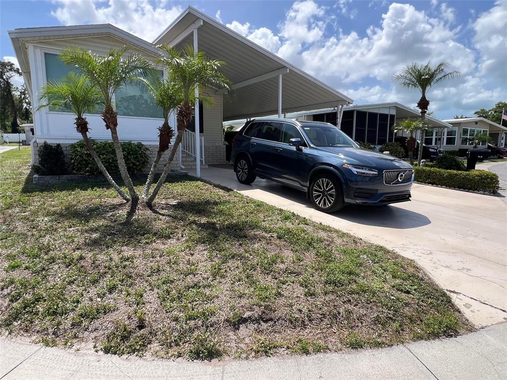 A dark blue SUV is parked in the driveway of a manufactured home with palm trees — 29250 US HIGHWAY 19 N UNIT 434, CLEARWATER, FL